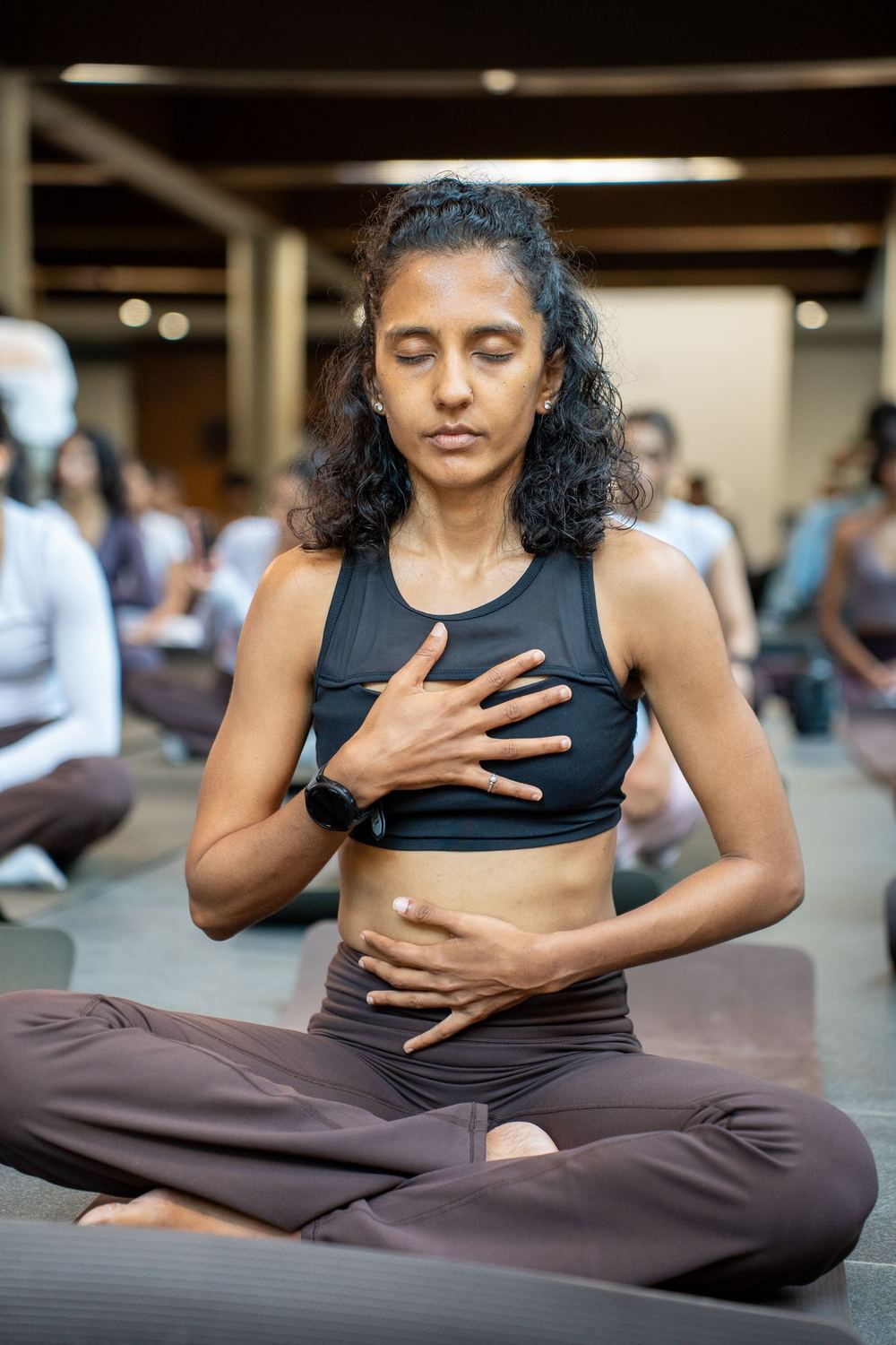 Shruthi Jain seated in a breath practice, one hand at her chest and one at her belly